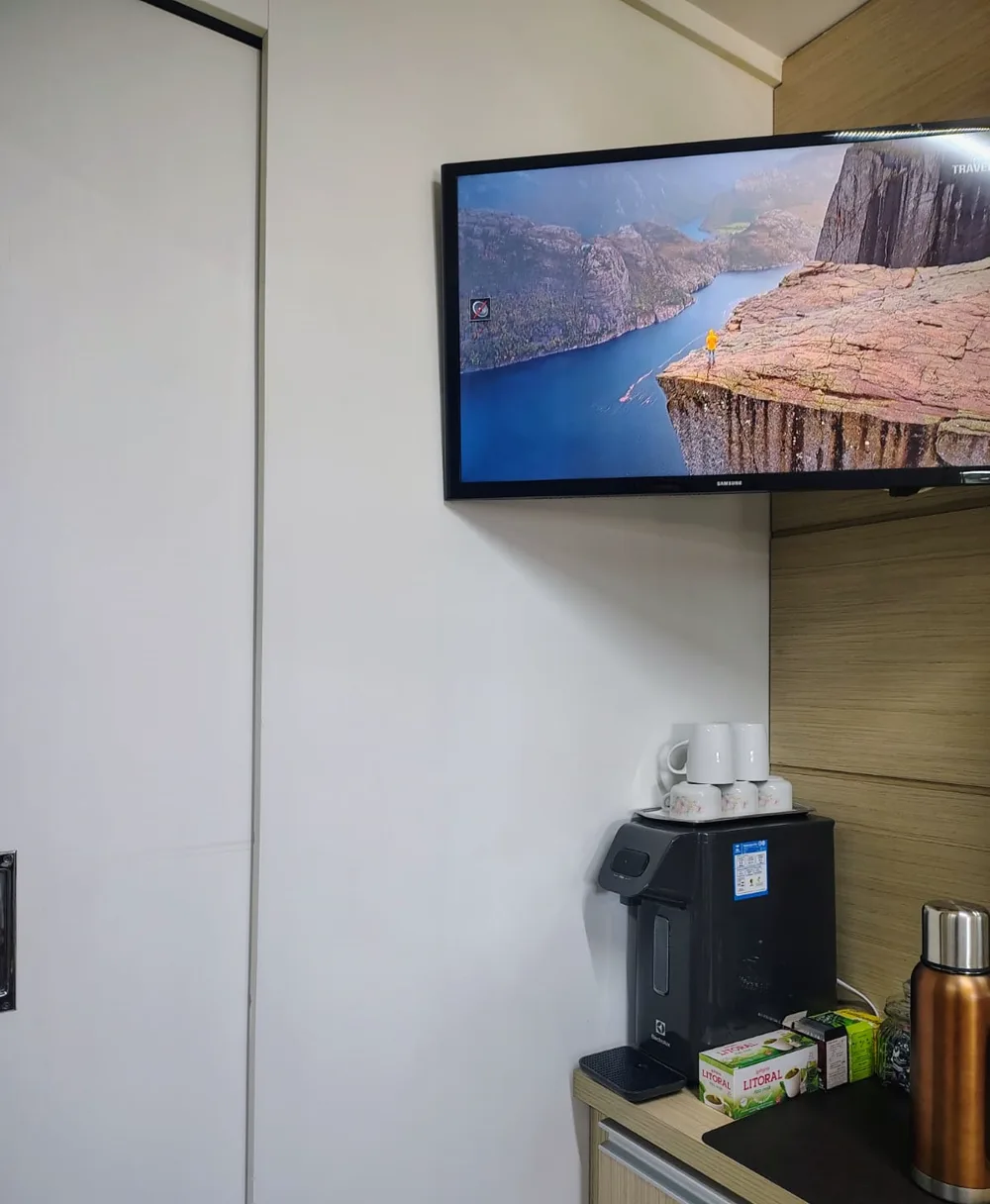 Espaço de espera com TV e café no studio em Caxias do Sul